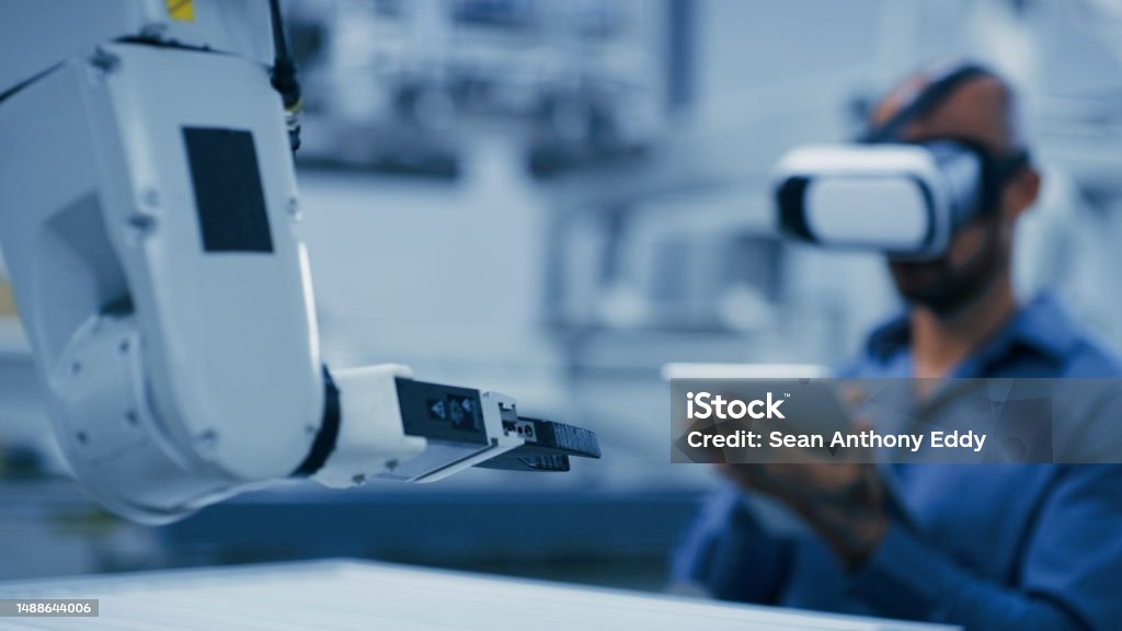 Engineering, robot arm and man with vr glasses and tablet for ai, futuristic electronics and manufacturing industry 4.0. Robotics workshop of technician person in digital, virtual reality and machine Artificial Intelligence Stock Photo