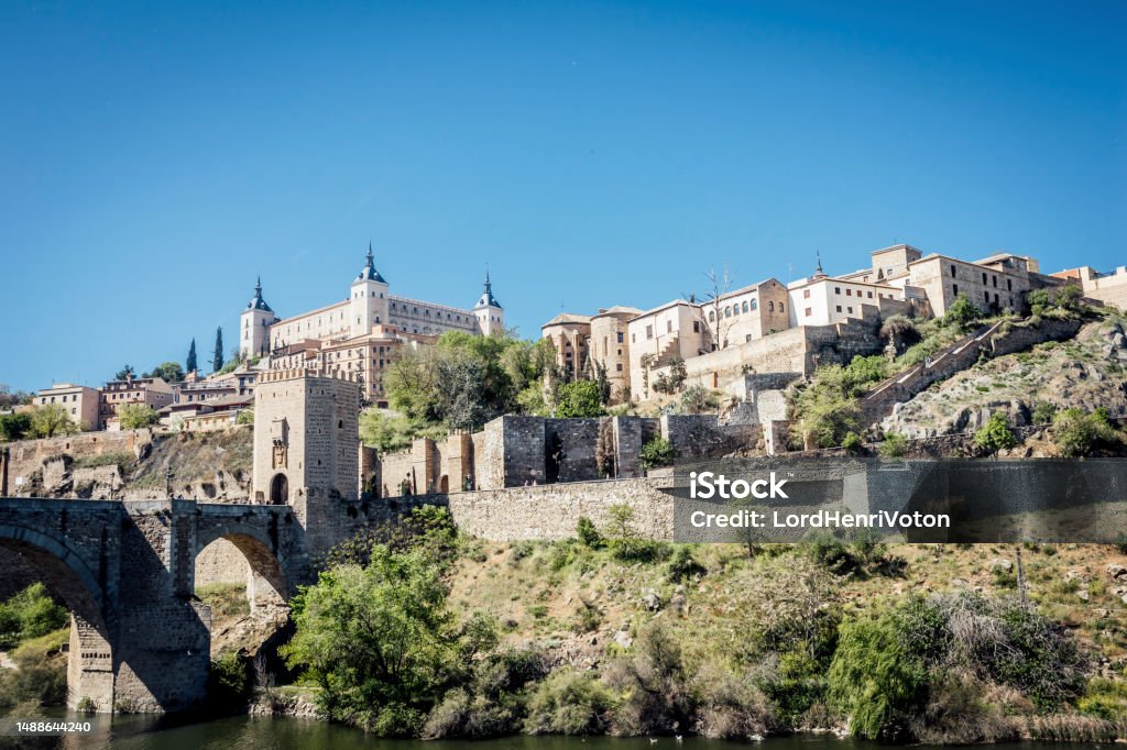 Cityscape of Toledo, Spain Panoramic cityscape of Toledo with Alcantara bridge over Tagus river, the city wall and the Alcazar. Castilla La Mancha, Spain Alcantara - Spain Stock Photo
