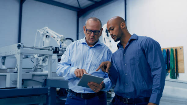 istock Engineering, tablet and men talking in lab with machine for analysis, research and automation. Technology, collaboration and engineer team on digital tech for robotic system, equipment and software 1488644401