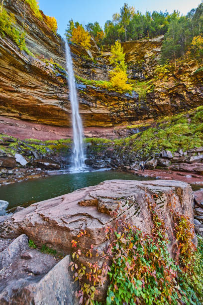 istock Beautiful tall waterfall over layered cliffs down to waters and large boulder with vines of red and green.jpg 1488645616