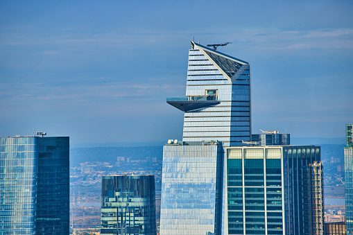 Image of Close shot of skyscraper tops with blue glass and blue hue sky and high balcony overlook