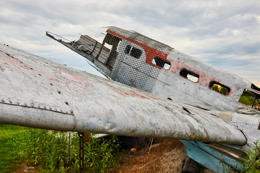 Image of Crashed and abandoned airplane wing detail in fields on cloudy day