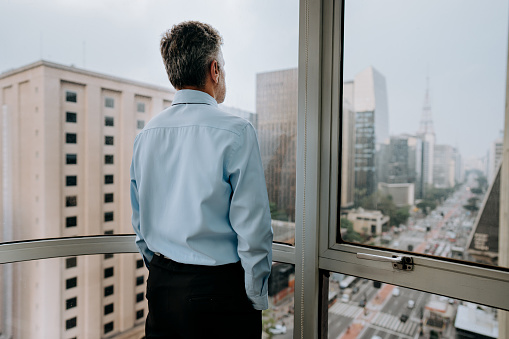 Portrait of a businessman with hands in pocket looking out at busy cityscape