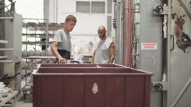 Worker pulling a cart through a ceramics factory