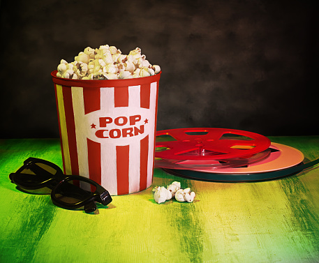 Cinema movies concept with a pop corn bucket, 3D glasses and film tape reel