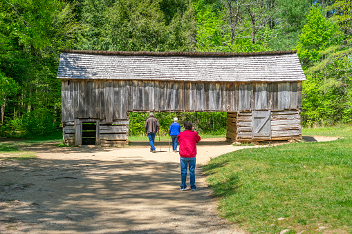 Cades Cove, Tennessee, United States  April 24, 2023: Horizontal shot of tourists examining the Cable Cantilever Barn in Cades Cove in April.