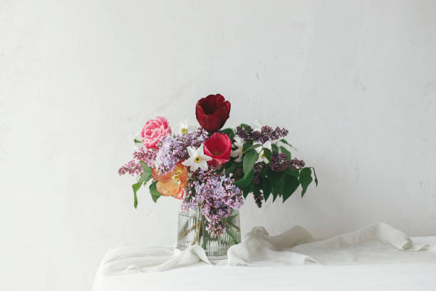 Happy Mothers day. Spring lilac, tulips, daffodils arrangement on soft fabric in modern rustic room. Stylish bouquet on rustic wooden table. Happy Womens day