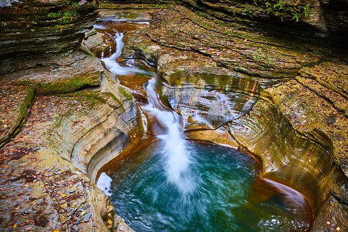 Image of Fall leaves cover terraced rocks in gorge with stunning blue water buckets and waterfalls