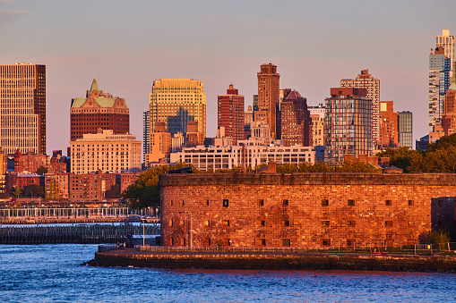 Image of Governors Island Castle Williams from waters in New York City golden hour sunset light