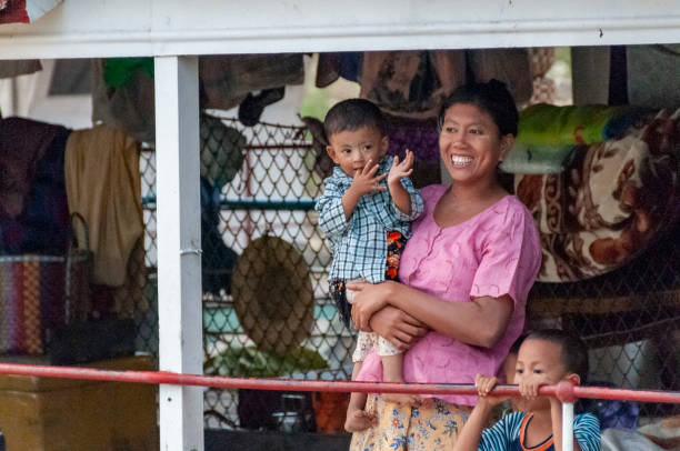 Irrawaddy River, Myanmar - nov 4, 2012: a woman holds her son in her arms as she waits for the ferry that connects Bagan to Mandalay on the Irrawaddy River to depart