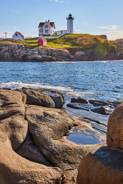 Reflection of Nubble Lighthouse in water at dusk, York, Maine, USA
