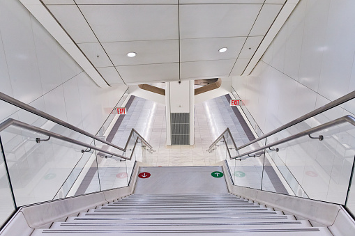Image of Modern clean white subway station stairs leading down to tracks with red and green arrow markers