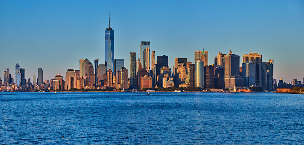 Image of New York City southern Manhattan panoramic skyline near sunset golden hour dusk from bay with One World Observatory