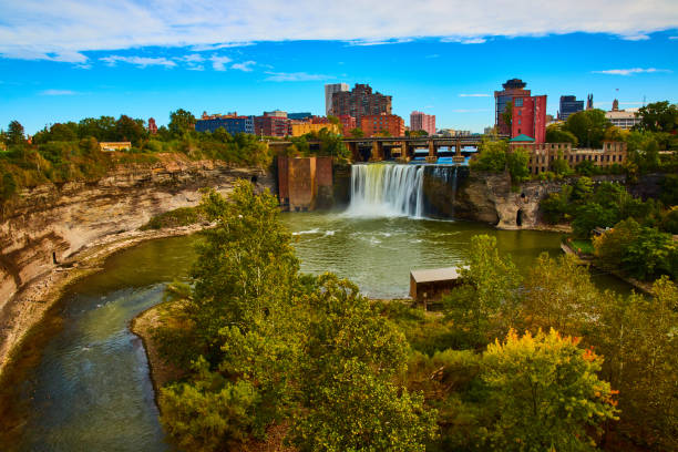 Rochester skyline along river and cliffs with waterfall pouring past bridge.jpg