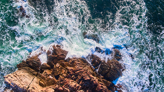 An offshore storm sends high, heavy, windswept ocean surf/breakers crashing up and over the coastal shoreline rocks at Peggy's Cove, Nova Scotia, Canada. Peggy's Cove lighthouse is in the background. Canon 5D Mark III.