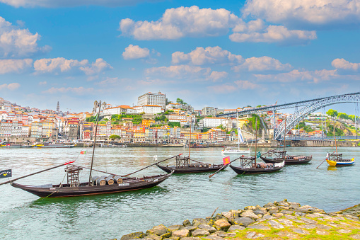 Porto, Portugal - May 3, 2023: old vinery ships at river Duoro with skyline of Porto in background and bridge ponte luis I in Gaia, Porto, Portugal.
