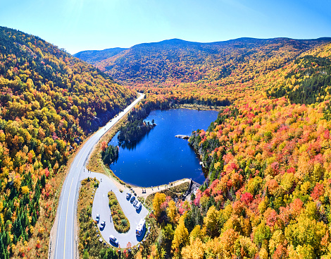 Image of Wide aerial panorama of blue lake and peak fall foliage mountains of New Hampshire along road with tourist overlook