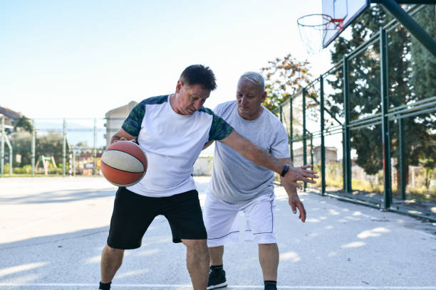istock Senior Male Blocking Friend While Playing Basketball Match Together 1488671269