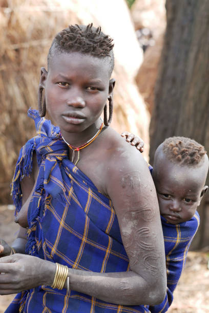 Woman from the Mursi tribe carrying her baby stock photo
