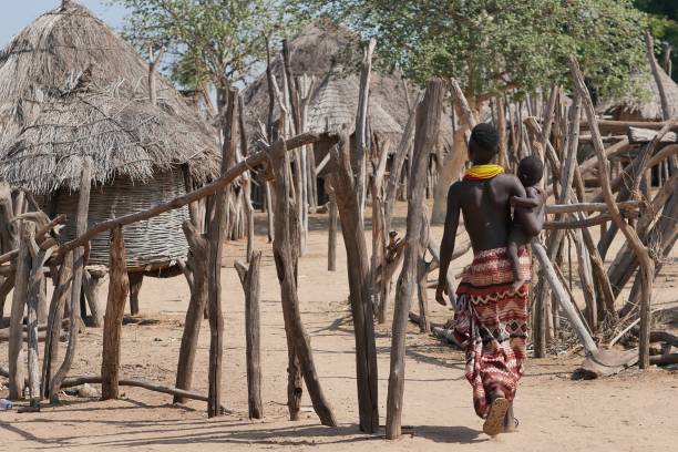 молодая женщина из племени каро несет своего маленького ребенка - africa ethiopia indigenous culture african tribal culture стоковые фото и изображения