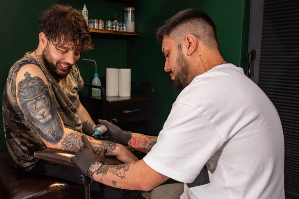 istock Professional tattooer doing tattoo on hand using tattoo machine in studio 1488678765