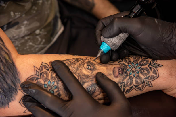 istock Professional tattooer doing tattoo on hand using tattoo machine in studio 1488678770