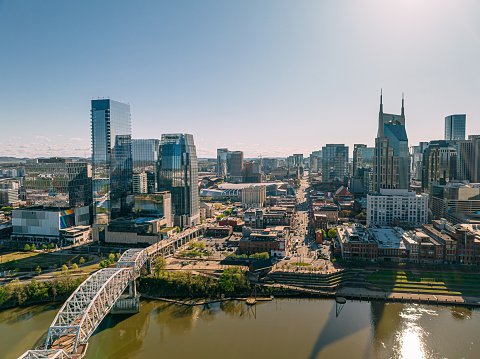 Aerial Point of View of Music City, Downtown Nashville, Tennessee from the North Side of the Cumberland River near Nissan Stadium.\n\nTourists make their way to Broadway, the center of Downtown Nashville. Tourists can be seen Walking across the John Seigenthaler Pedestrian Bridge in the bottom left.