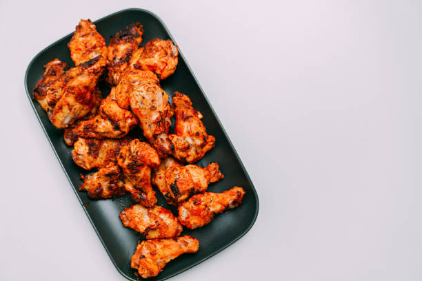 Close-Up Shot of Grilled Spicy Buffalo Chicken Wings on a White Table and Dark Gray Plate
