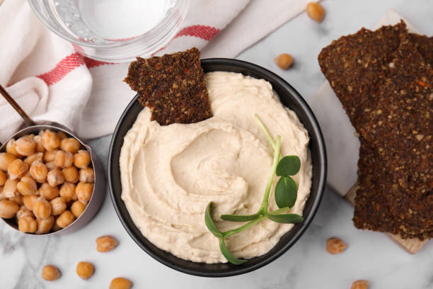 istock Delicious hummus with crispbread served on white marble table, flat lay 1488698300