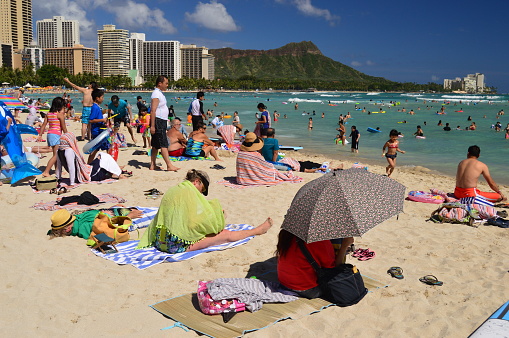 Waikiki Beach, HI, USA July 31 Beach goers crowd every inch of sand near the water on a sunny summer vacation day on Waikiki Beach, Hawaii
