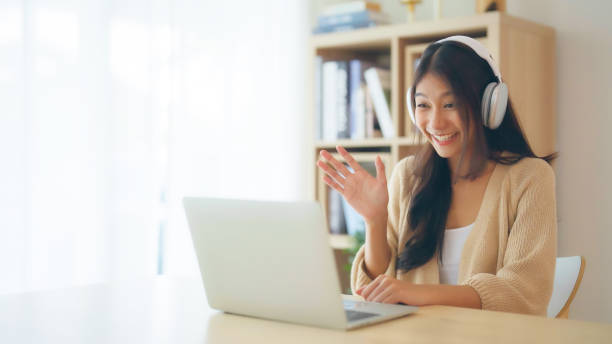 istock Young asian woman wearing headset while working on computer laptop at house. Work at home, Video conference, Video call, Student learning online class 1488702899