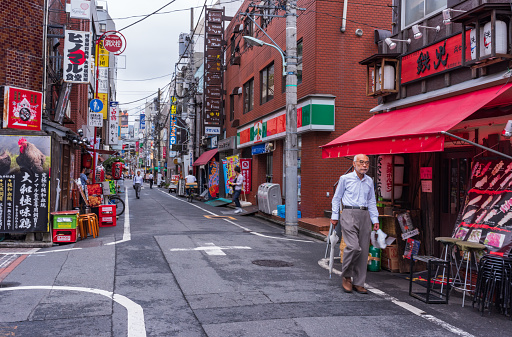 Tokyo, Japan - July 14, 2016: Elderly man walks past shops in Tokyo back street.