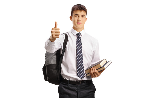 Teenage male student holding books and showing thumbs up isolated on white background