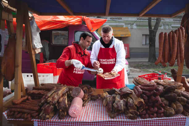 киоск мясника на рынке slaninijada kacarevo, продающий колбасы, копченое и вяленое мясо, а также сушеную свинину, также называемую на сербском языке su - market market stall shopping people стоковые фото и изображения