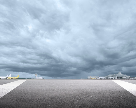 Empty airport runway  with airport terminals and cloudy sky