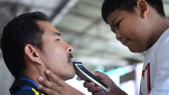 Cutting beard with electric razor son give father