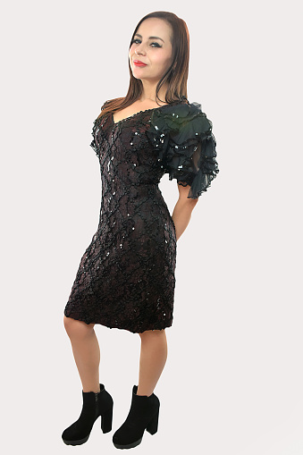 Portrait of a young adult model with black night spangle dress poses on a studio white background and plays with her long brown hair during photoshoot