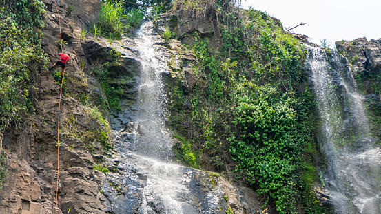 Man rappelling down a waterfall in Matagalpam Nicaragua Central America without protective gear