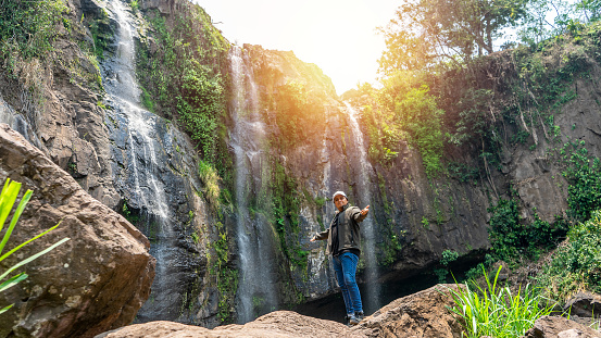Latino man in front of a waterfall exploring the mountainous area of Central America, in Matagalpa, Nicaragua