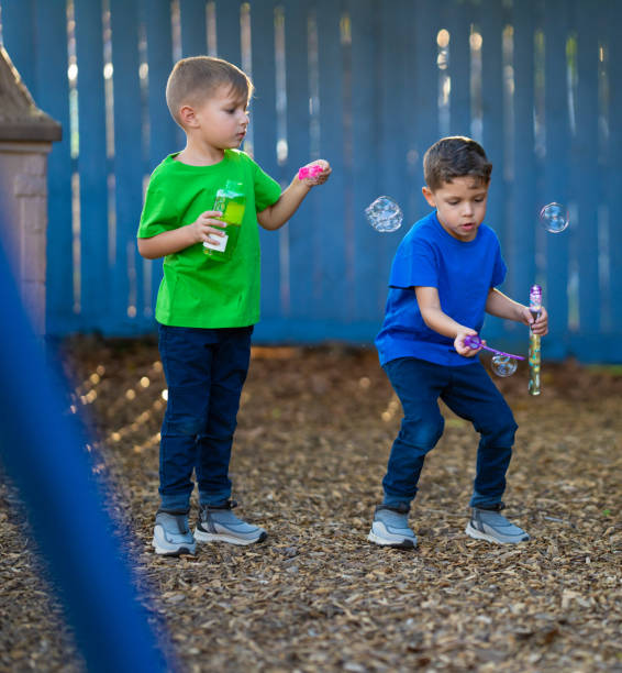 istock Two hispanic brothers having a fun time playing with water and soap bubbles 1488728873