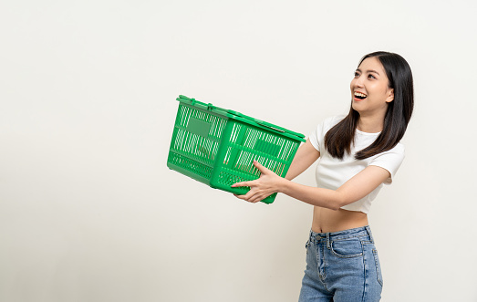 Happy beautiful woman holding shopping basket. Portrait beautiful asian female in fashion style standing pose on isolated background. Young asian woman shopping at online market application