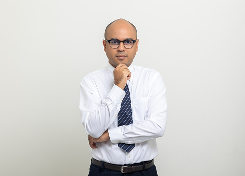Portrait of Young asian businessman thinking on isolated white background. Handsome middle aged Indian businessman in office uniform.