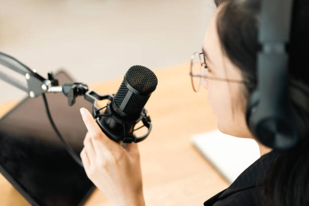 istock Content creator woman host streaming her a podcast with headphones and microphone interview cheering guest conversation at broadcast studio. Blogger motivation recording voice over radio. 1488733272