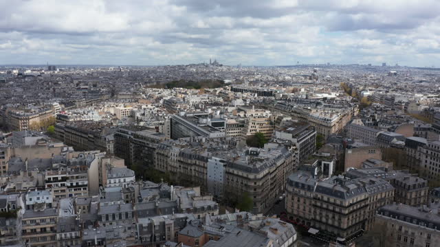 Aerial above Paris building rooftops to reveal Arc de Triomphe monument in Paris, France