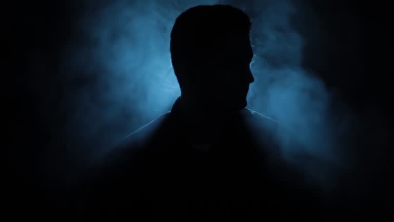 Close-up creative shot of a man sitting on a chair with rim light creating a silhouette, Hd footage.