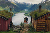 Rear view of couple contemplating scenic mountain valley with old wooden houses in Norway