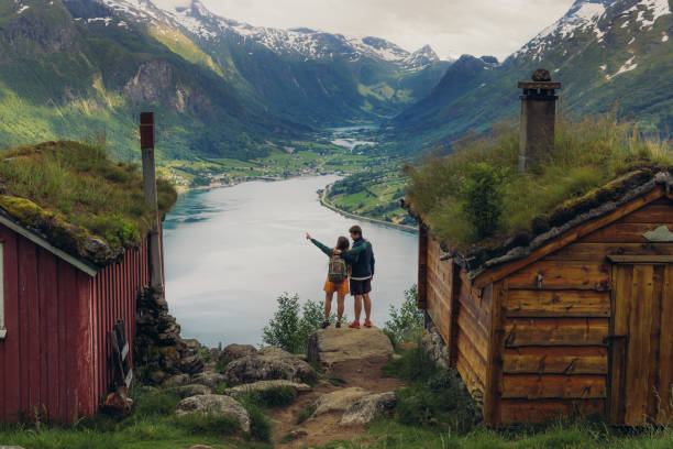 Rear view of couple contemplating scenic mountain valley with old wooden houses in Norway stock photo