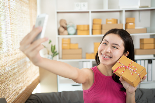 Woman uses his phone to take pictures of himself with products or selfies, Identity verification or order confirmation, Business style for working at home, Working at home and owning businesses.