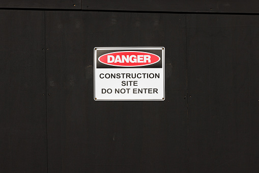 Danger, construction site sign on a black wall.