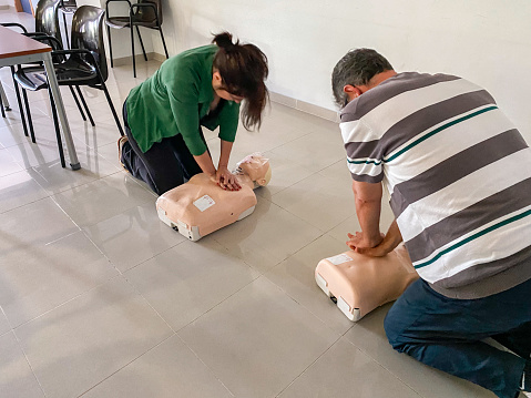 Woman and man practicing CPR trainning on a dummy